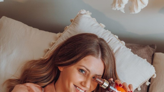 A woman in bed holding a Kerastase bottle.